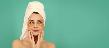 Güzel yüzlü kadın, yüz portresi. Genç kadın gülüşünün yüzünde havluyla kolajen altın göz bantları vardır. Güzel kadın, izole edilmiş yüz portresi, taklit alanı olan pankart.