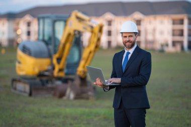 Kazıcının yanında inşaat işçisi. Evin önünde kendine güvenen bir inşaat sahibi. Mimar, inşaat mühendisi. İnşaat alanında güvenlik yeleği ve kasketi olan bir inşaat sahibi.