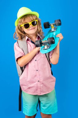 Çocukluk. Renkli arka planda kaykayı olan tatlı bir çocuk. Komik çocuk, stüdyoda kaykay tutan şık bir kaykaycı.