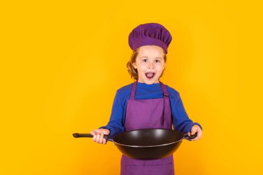 Çocuk aşçı aşçı aşçı. Aşçı bozuntusu aşçı. Önlüklü ve aşçı şapkalı çocuk stüdyo izole edilmiş arka planda sağlıklı bir yemek hazırlıyor. Yemek pişirme süreci