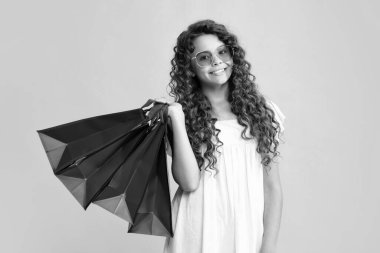 Yaz alışverişi. Sarı arka planda alışveriş torbaları olan güzel moda kızı. Alışveriş ve moda alışverişi. Alışveriş çantalı çocuk. Gülümseyen kız