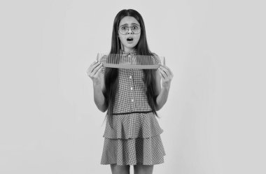 Şaşırmış genç kız. Sarı izole edilmiş stüdyo arka planında saçlarını tarayan çocuk. Saç fırçası olan genç bir kız. Çocukların saç stili