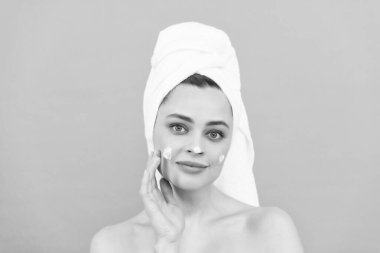 pozitif genç bayan mavi arka plana yüz kremi sür.