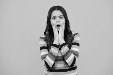 Şaşırmış bir yüz, genç bir kızın şaşırmış duyguları. Ergenlik çağındaki tatlı bir kız vesikalığı. İzole edilmiş arka planda çocuk portresi. Güzel ergen yüzü