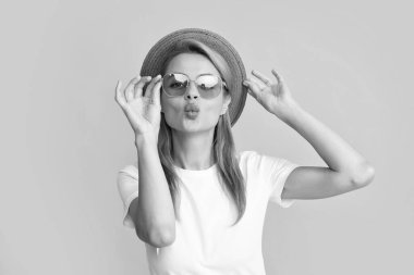 Young redhead woman in straw hat, surprised expression, isolated on yellow background. Summer lifestyle studio portrait. Redhead girl sends an air kiss