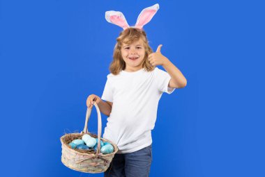 Çocuk için Paskalya. Paskalya yumurtası ve sepeti tutan tavşan kulaklı mutlu bir ergen çocuk. Paskalya çocukları tatil konsepti