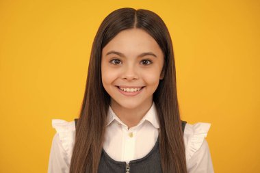 Portrait of beautiful happy smiling teenage girl on yellow studio background