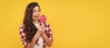 Mutlu kız lolipopu tutar. Lolipop çocuk. Uzun kıvırcık saçlı hippi çocuk lolipopu yaladı. Çubukta şeker. Karamelli şeker dükkanı. Tatlı çocukluk hayatı. Genç diş bakımı. Tatlı düşkünü. Lezzetli.