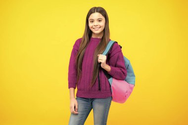 Okul üniformalı, sırt çantalı bir kız. Sarı izole edilmiş genç kız öğrenci. Öğrenim ve eğitim çocukları