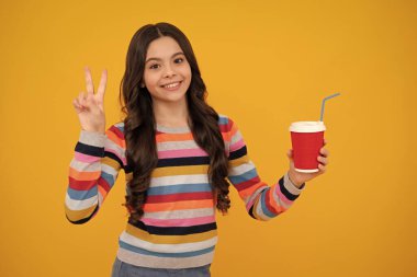 Genç kız elinde bir fincan sıcak kahve ya da çay tutuyor. Sarı arka planda paket bardağı olan çocuk, sabah enerji içeceği içeceği. Mutlu ergen, pozitif ve gülümseyen genç kız duyguları