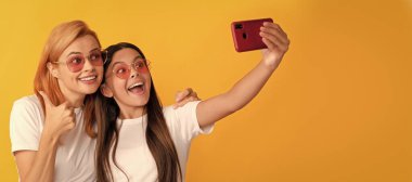 Mother and daughter child banner, copy space, isolated background. stylish mom and kid bloggers. happy woman and girl take selfie with smartphone. selfie family