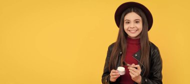 Şapkalı gülümseyen çocuk makyaj fırçası ve sarı arka planda pudra, makyaj. Genç çocuklar için makyaj malzemeleri, poster tasarımı. Güzellik çocukları makyaj, fotokopi alanı ile pankart