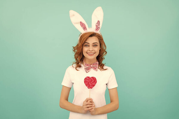 glad easter woman wear bunny ears hold heart lollipop.