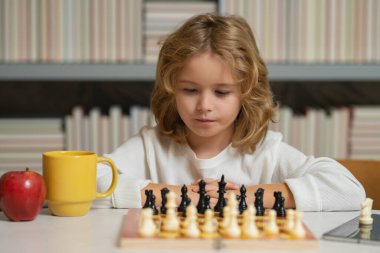Konsantre çocuk satranç stratejisi geliştiriyor, masa oyunu oynuyor