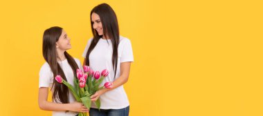 Anne ve kız çocuk afişi, kopyalama alanı, izole edilmiş arka plan. 8 Mart. Sarı arka planda lale çiçekleri olan mutlu anne ve kız.