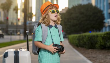 Seyahat çantalı çocuk tatilde. Çocuk gezisi ve macera konsepti. Küçük çocuk elinde valiziyle tatile çıkıyor.