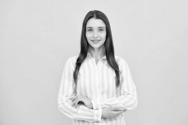 Pretty woman in shirt looking with satisfaction. Studio shot of beautiful woman isolated against yellow background