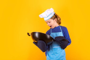 Çocuk aşçı tavayla yemek pişirir. Şef çocuk sağlıklı yemek hazırlıyor. Şef şapkalı çocuk portresi