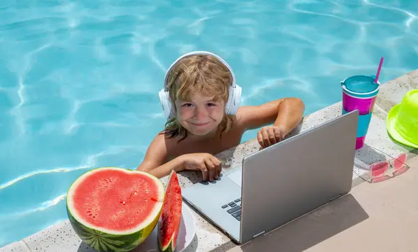 Child with laptop in swimming pool in summer day. Work outside concept, Business and summer