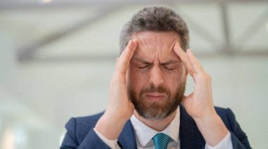 Aşırı yorgun adam migren ağrısı çekiyor. Sıkılmış iş adamının ofis sendromu var. Migreni ya da baş ağrısı olan bitkin bir adam. Ofis çalışanı, yönetici ya da serbest çalışan birinin başı ağrıyor.