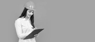 İzole edilmiş bir yüz portresi, taklit alanı olan bir afiş. Panosu olan iş kadını, gri üzerine bir portre. Kasklı kadın işçinin portresi.