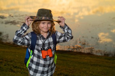 Dürbünlü çocuk doğa yürüyüşü yapıyor. Küçük kaşif. Çocuklarla açık hava eğlencesi ve maceralar. Güneşli kırsal kesimde çocuk turist