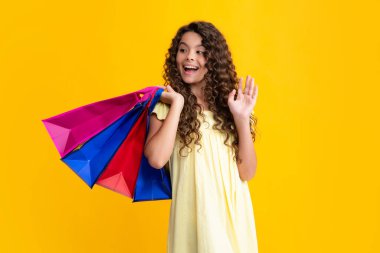 Happy teenager portrait. Funny teen girl hold shopping bag enjoying sale isolated on yellow. Portrait of teenager schoolgirl is ready to go shopping. Smiling girl