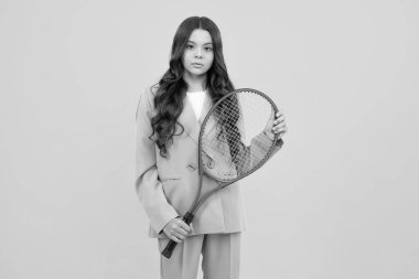 Genç tenisçi çocuk tenis raketini izole edilmiş sarı stüdyo arka planında tutuyor. Çocuklar için spor ve spor. Moda ve spor konsepti