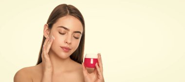 Kadın yüzü, yakın portre, kopyalanmış afiş. Temizleme fırçası. Bayan kozmetik ürünü sunuyorum. Kadın yüz kremi sürüyor.