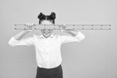 Okul ekipmanlarını ölçüyorum. Geometri dersi için ölçü tutan liseli kız, mavi arka planda izole edilmiş. Öğrenci matematiği okuyor. Mutlu ergen, liseli kızın pozitif ve gülümseyen duyguları