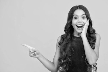 Wow, its unbelievable. Shocked teenager child pointing aside at copy space. Teen girl pointing with two hands and fingers to the side. Excited face, cheerful emotions of teenager girl