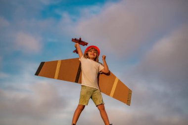 Çocuk günü. Oyuncak uçakla sahada eğlenen bir çocuk. Uçakla uçan çocuk pilot yazın doğada seyahat etmeyi hayal ediyor.