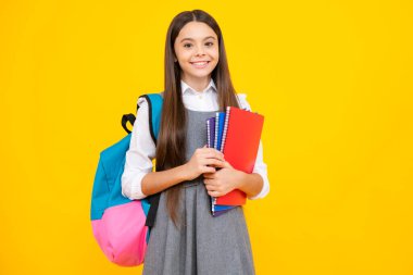 Okula dönelim. Liseli kız, sarı izole stüdyo geçmişi üzerine kitap tutuyor. Okul ve eğitim kavramı. Okul üniformalı ergen kız.