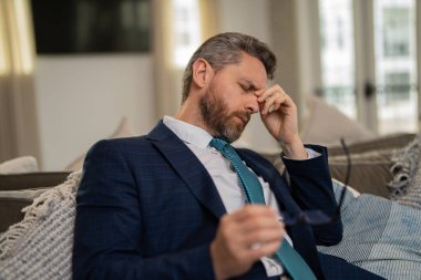 Aşırı yorgun adam migren ağrısı çekiyor. Sıkılmış iş adamının ofis sendromu var. Migreni ya da baş ağrısı olan bitkin bir adam. Ofis çalışanı, yönetici ya da serbest çalışan birinin başı ağrıyor.