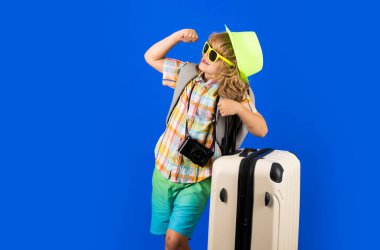 Stüdyo arka planında bavulu olan çocuk gezgin. Turist çocuk. Seyahat çantasıyla çocuk portresi. Seyahat, macera, tatil