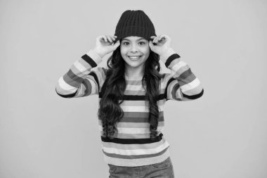 Winter hat. Cold season concept. Winter fashion accessory for children. Teen girl wearing warm knitted hat. Happy teenager, positive and smiling emotions of teen girl