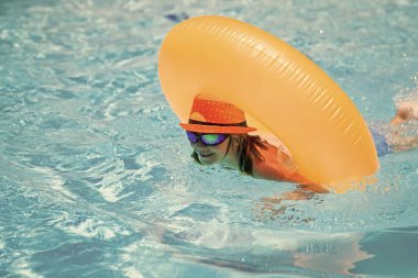 Yüzme havuzunda şişme yüzük takan çocuk. Çocuk tropik tatil köyü havuzunda yüzüyor. Sıcak yaz. Çocuklar için su oyuncakları ve şamandıralar