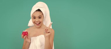 amazed kid in bath tower applying skin cream, cosmetic. Cosmetics and skin care for teenager child, poster design. Beauty kid girl banner with copy space