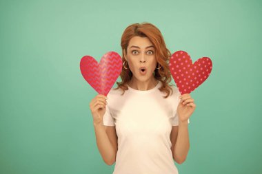 shocked young lady with red heart on blue background.