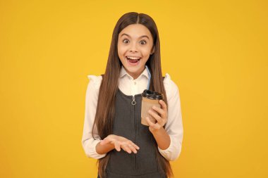 Sarı stüdyo arka planında kahve ya da çay fincanı olan çocuk. İçki ısmarlayan ergen kız.