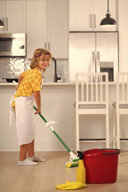 Çocuk yerleri temizliyor. Ev işlerine yardım eden, evi temizleyen çocuk portresi. Oda servisi, ev işleri.