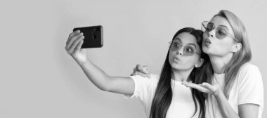 Anne ve kız çocuk afişi, kopyalama alanı, izole edilmiş arka plan. Mutlu kadın ve kız akıllı telefonla selfie çekiyorlar. Selfie ailesi. modern yaşam