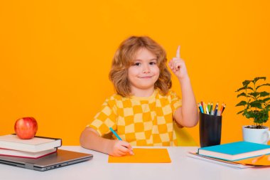 Okullu çocuk harika bir fikirle işaret parmağını kaldırıyor. İlkokuldan elinde kitapla bir çocuk. Küçük öğrenci, zeki inek öğrenci çalışmaya hazır. Okula ilk gelişim.