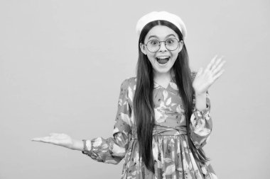 Teenager child pointing to the side with a finger to present a product or idea. Teen girl in casual outfit pointing empty space. Excited teenager, amazed and cheerful emotions