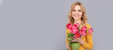 Laleli mutlu bir kadın. Bayan bahar tatili için çiçekleri saklar. Buketli gülümseyen kız. İzole edilmiş yüz portresi, taklit alanı olan pankart