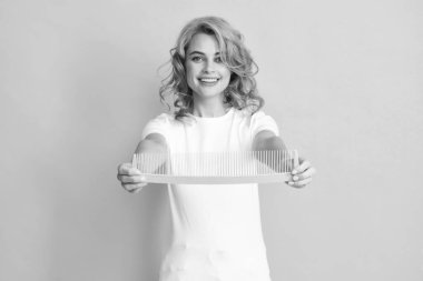 Sarı arka planda izole edilmiş taraklı kızıl saçlı kadın. Taraklı genç bayan kuaför.