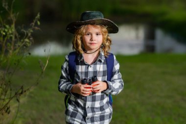 Gezgin şapkalı ve sırt çantalı izci çocuk. Dürbünlü kaşif ve macera
