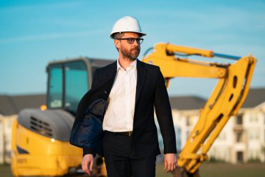 İnşaat mühendisi inşaat alanında çalışıyor. Evin arka planındaki mühendis. Modern ev inşaatında kendine güvenen mühendis. İspanyol inşaat mühendisi miğferinde