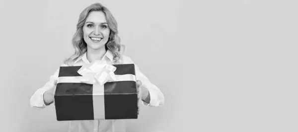 stock image cheerful woman with big present box on yellow background. Woman isolated face portrait, banner with mock up copy space