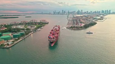 Konteyner gemisi. Miami 'de konteynırlı kargo gemisi, insansız hava aracı manzaralı. Konteynır Miami, Florida 'daki kargo gemisine yüklendi. Limandan ayrılan hava görüntülü kargo gemisi. Kargo mavnası işi 4k.